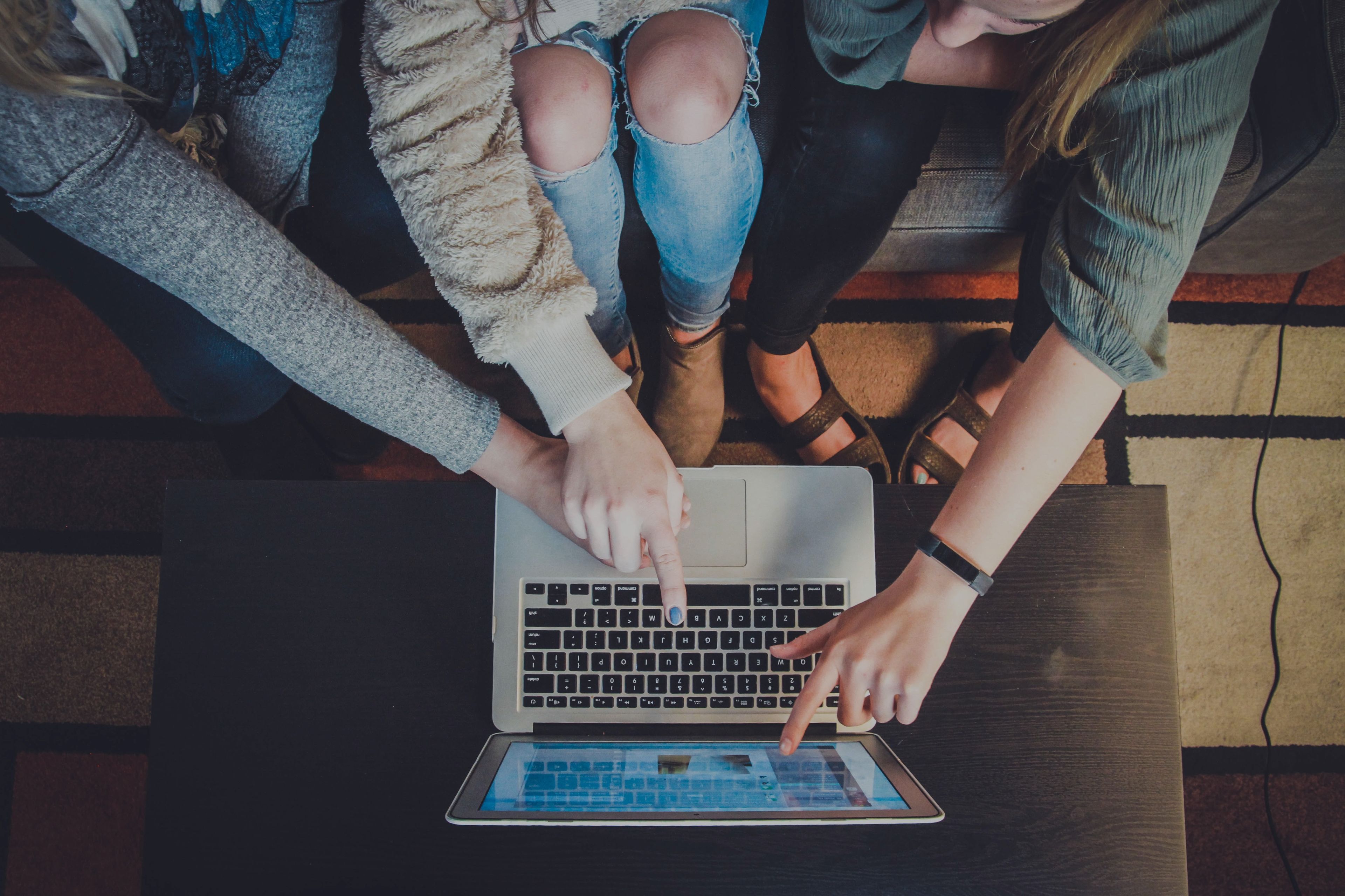 Three students pointing at a laptop monitor