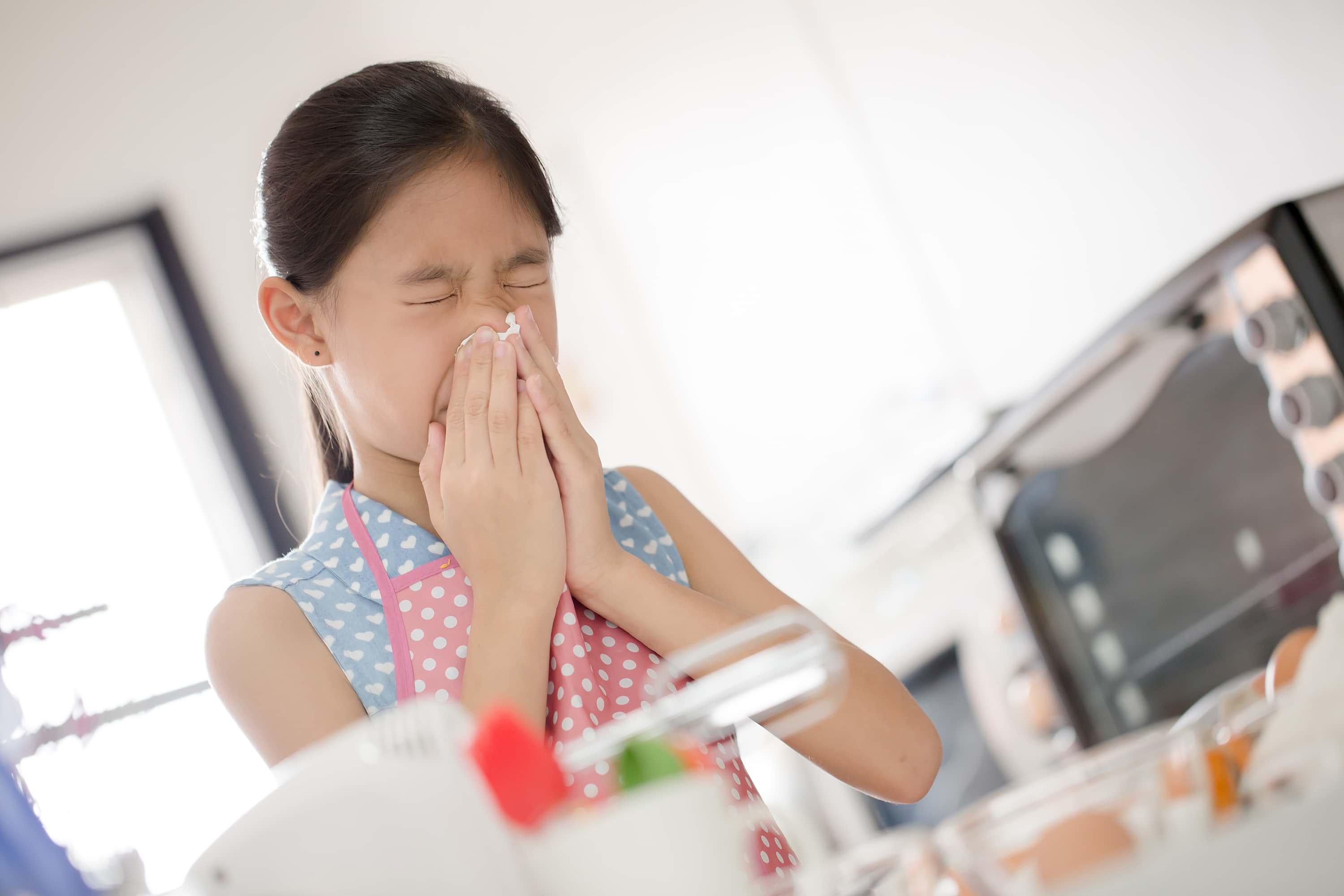 Child sneezing in kitchen
