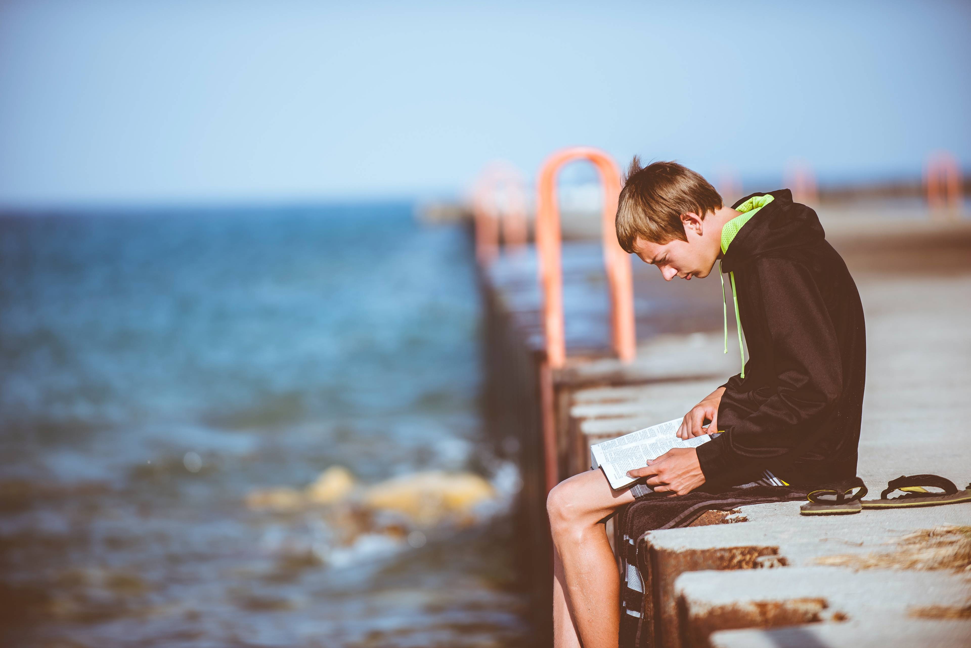 man writing on a notepad, sitting on dock