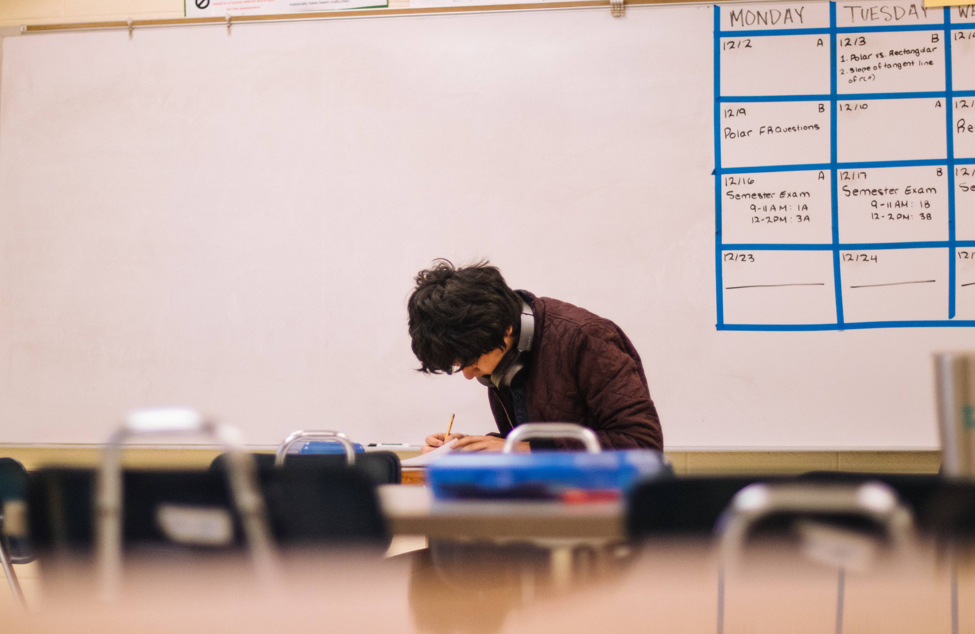 professor in a classroom, looking down and writing