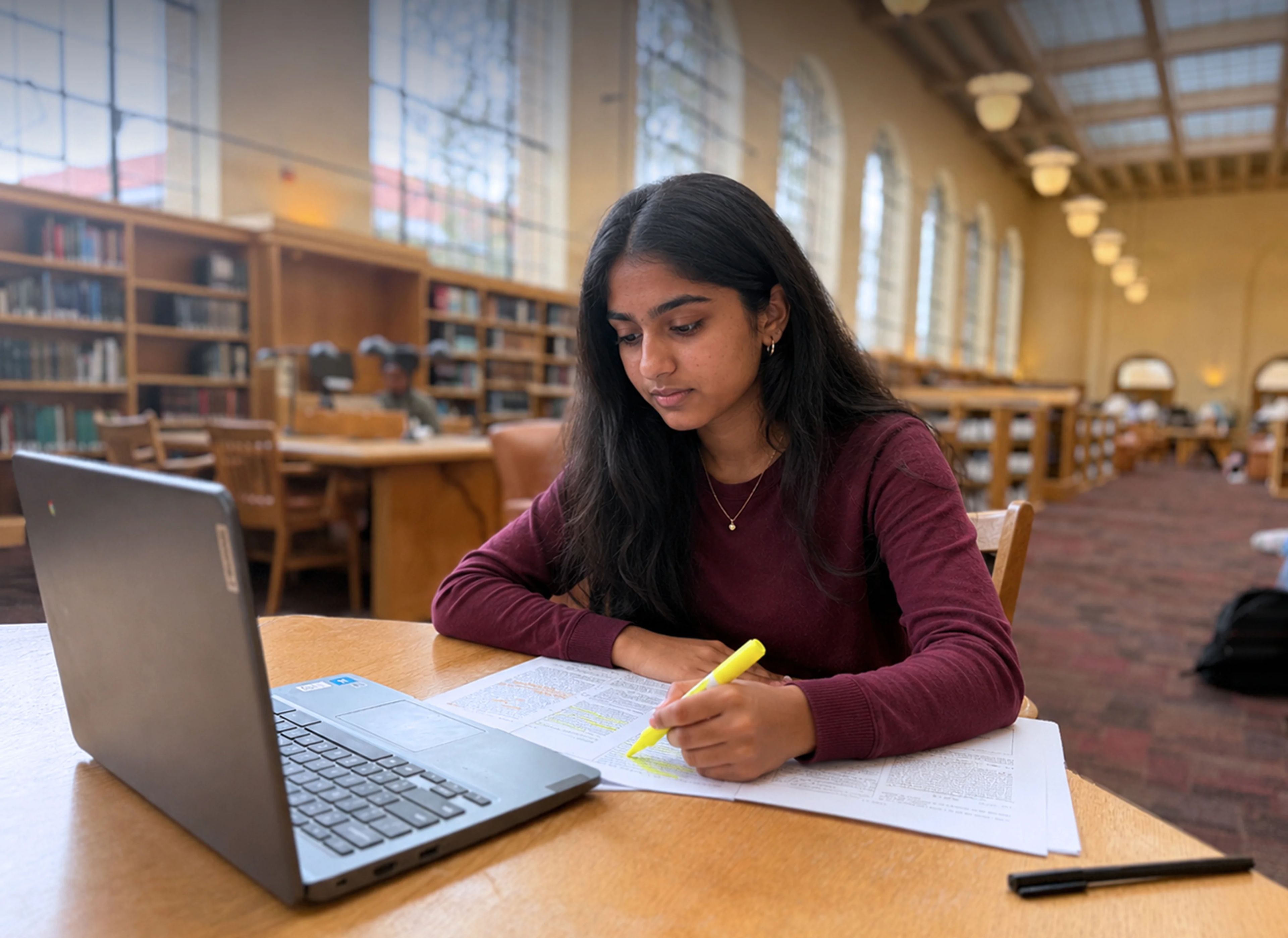Indian high school student reading research papers in the library