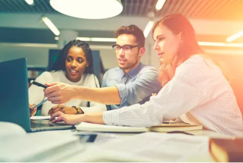 Image of three researchers looking at an exciting finding on a computer. 