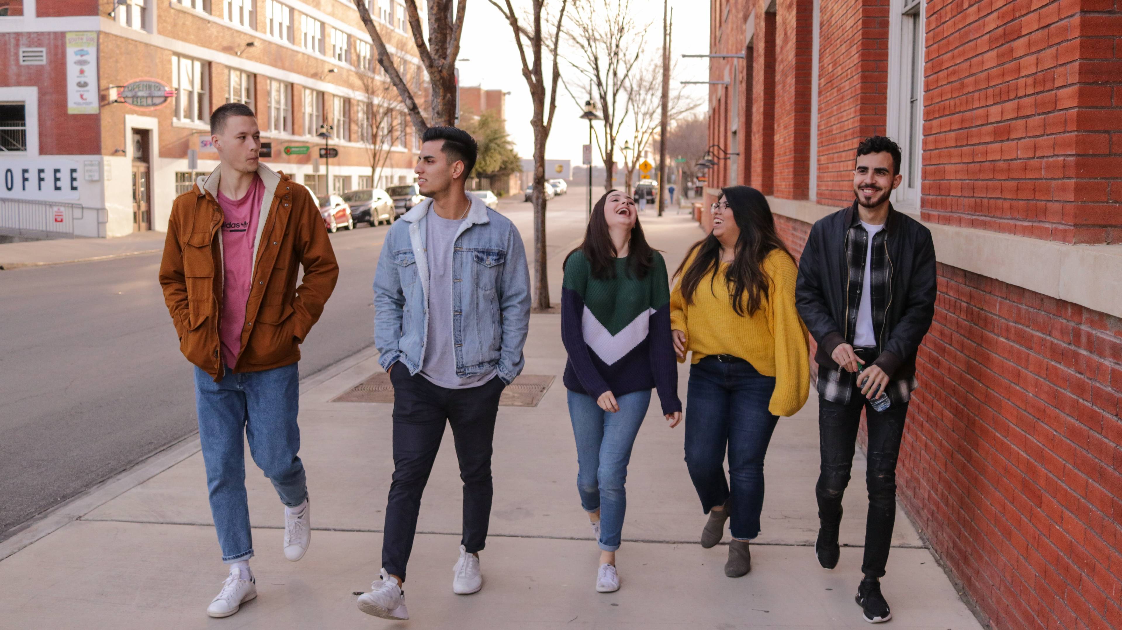 young adults walking down the street wearing jackets