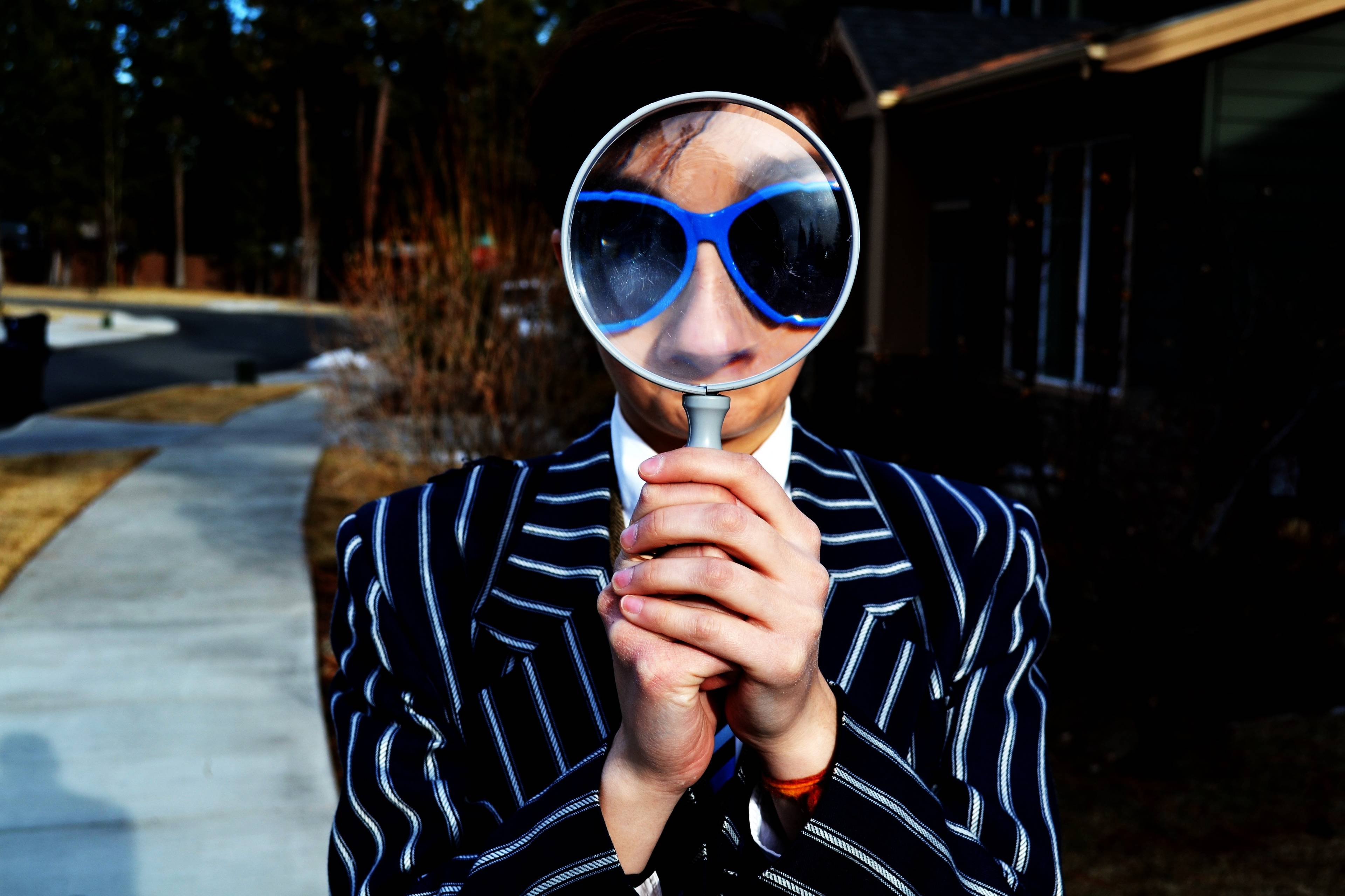 young person in a suit looking through a magnifying glass