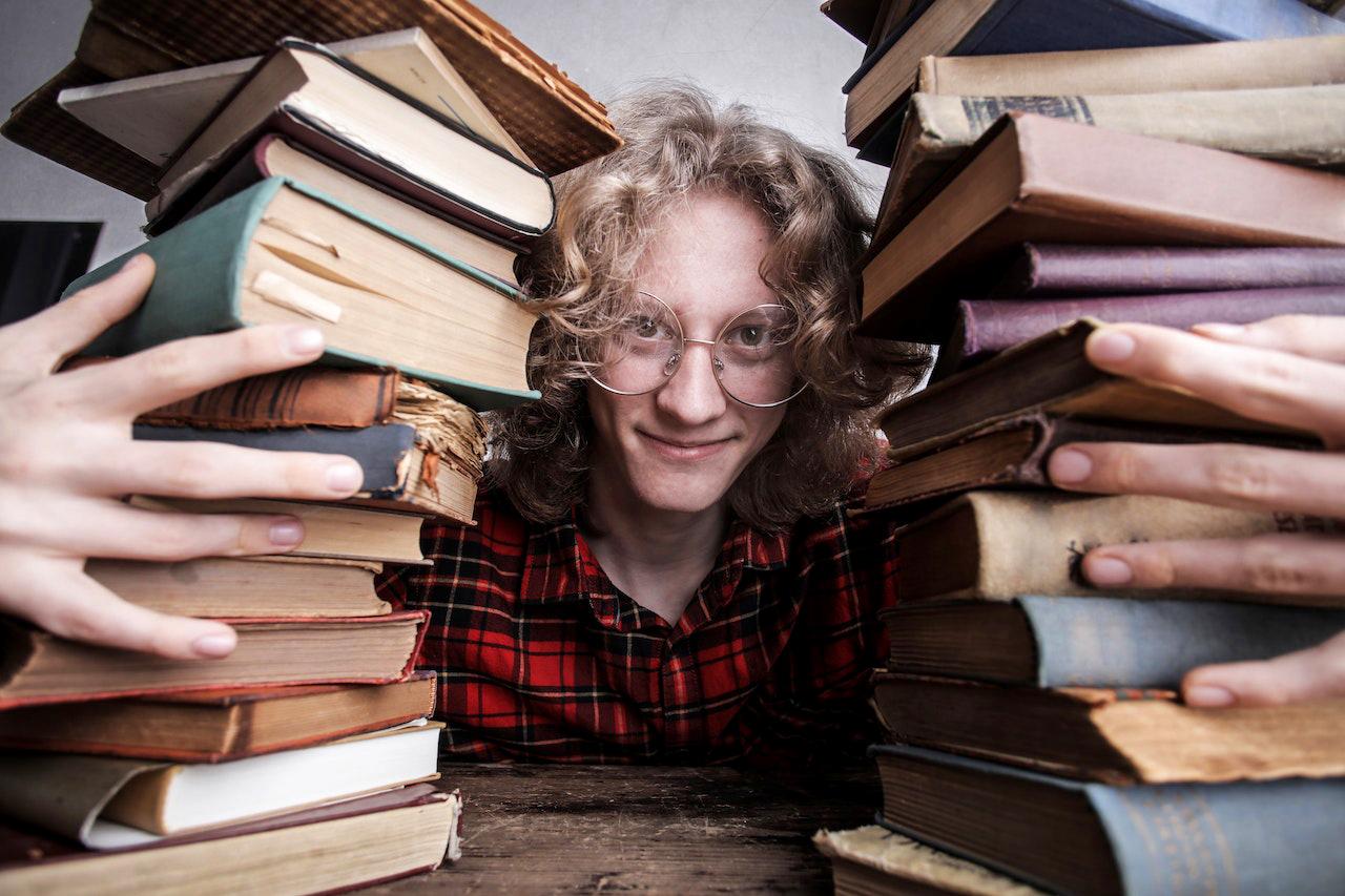 Male student smiling with lots of books