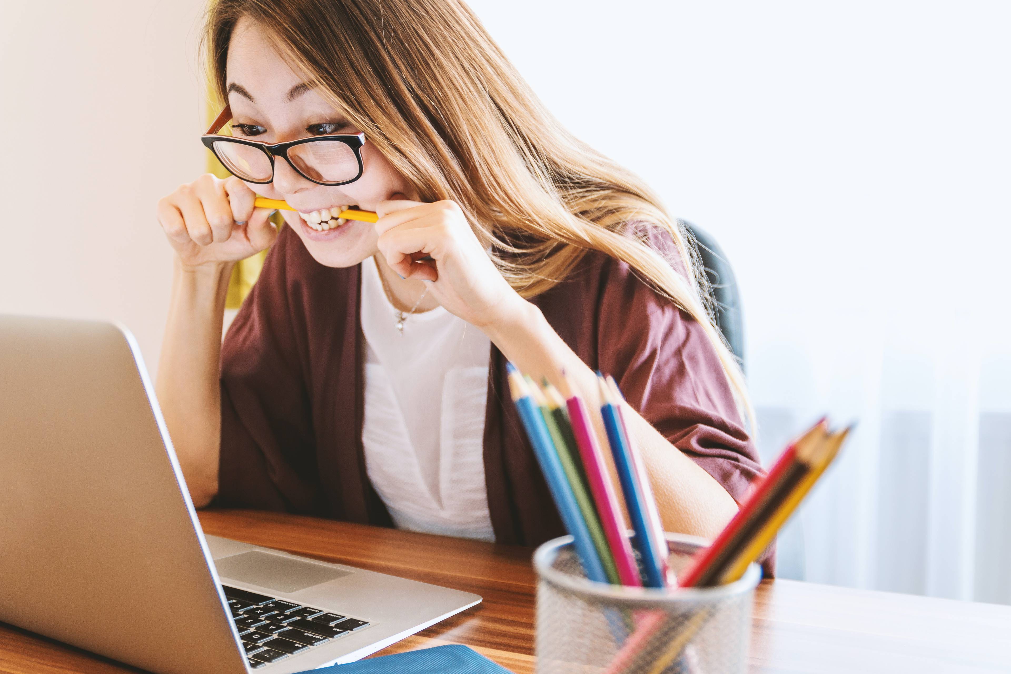 woman with glasses nervously looking at computer screen